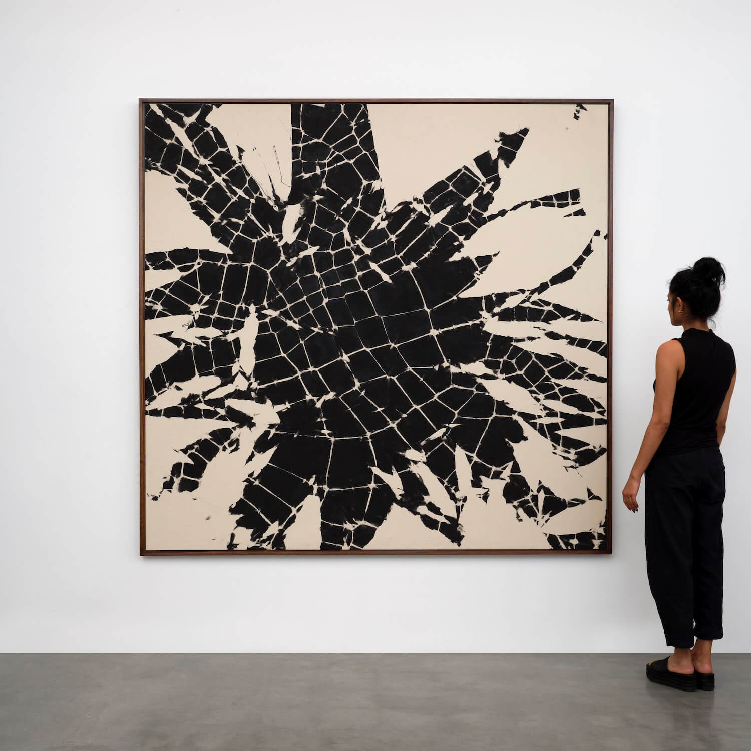 a woman stands in front of a black and white abstract painting